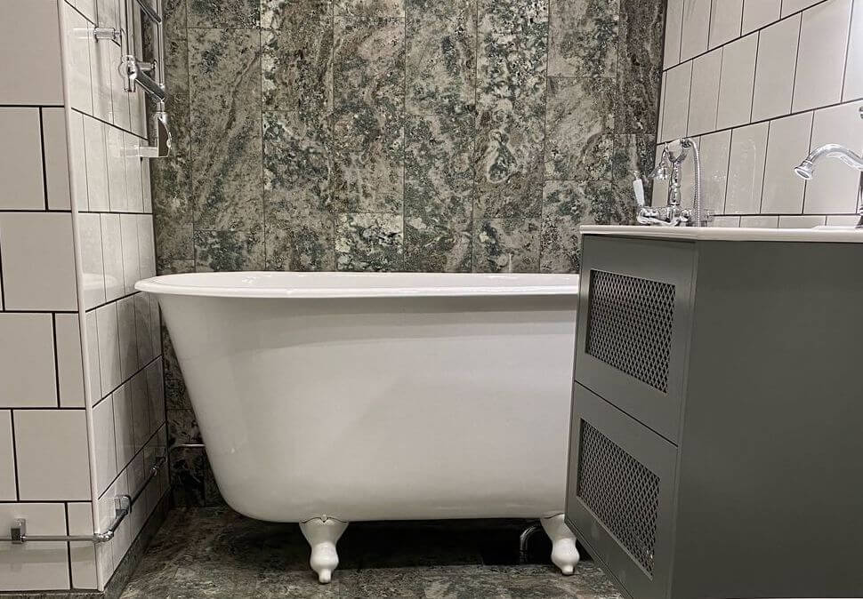 Nyrenoverat badrum med grön marmor och badkar