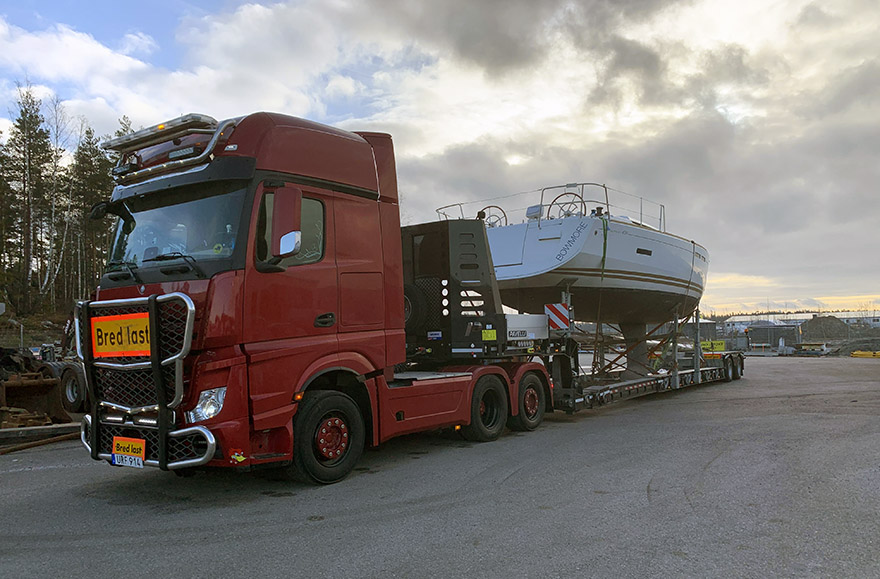 En röd lastbil kör en båttransport.