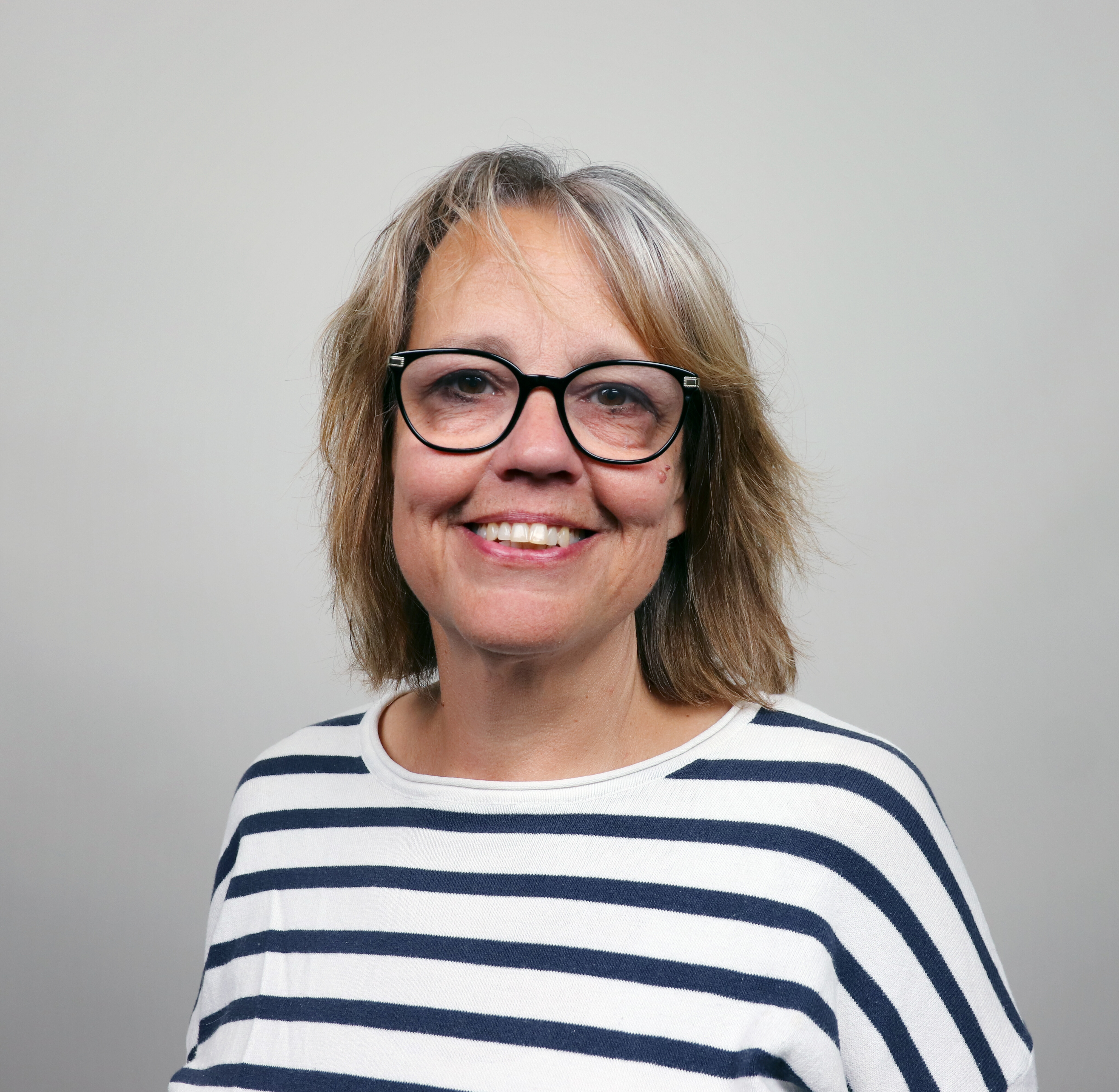 Porträtt på Maria Jorfors, en kvinna med glasögon, brunt halvlångt hår och svart blus.